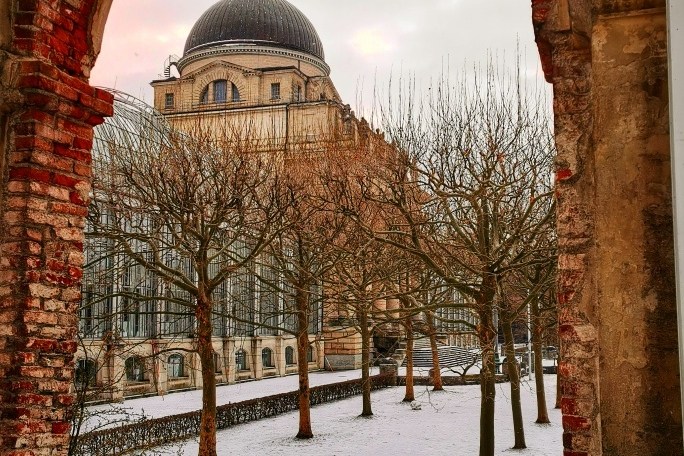 a view of trees on a snow covered field near a building