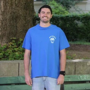Mathew a man in a blue shirt standing in front of a building