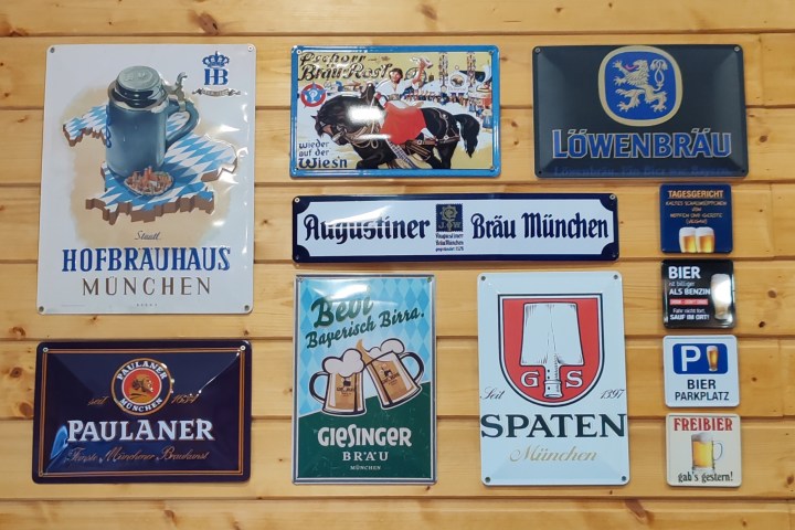 Collection of vintage Bavarian beer signs on a wooden wall.