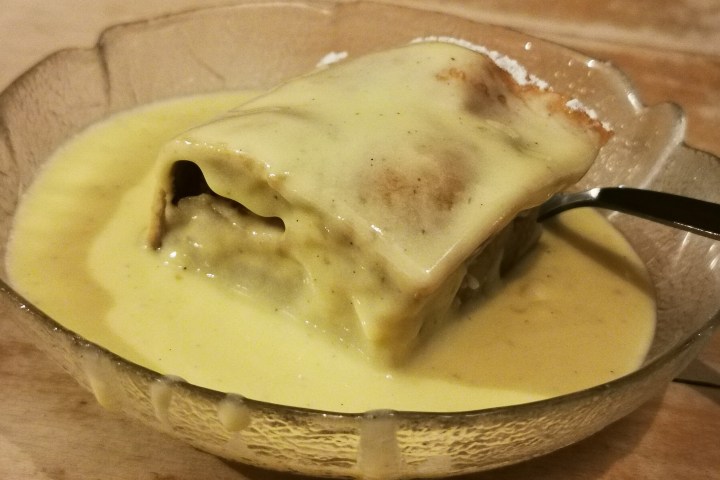Dessert with thick yellow sauce in a bowl, partially covering a pastry.