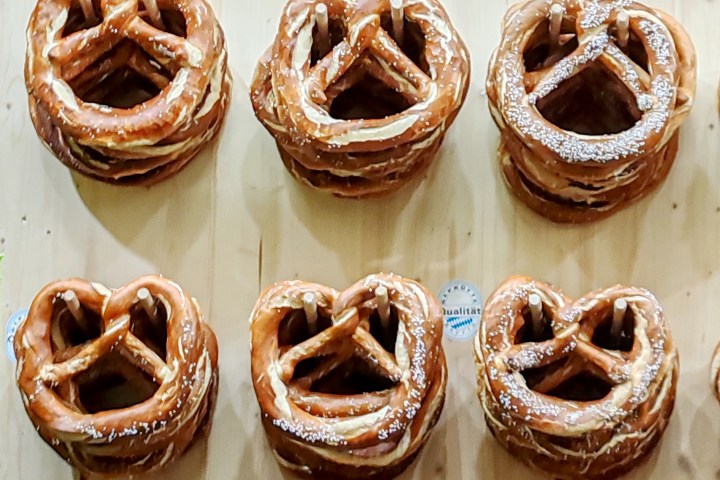 Stacks of large pretzels on display on a wooden surface.