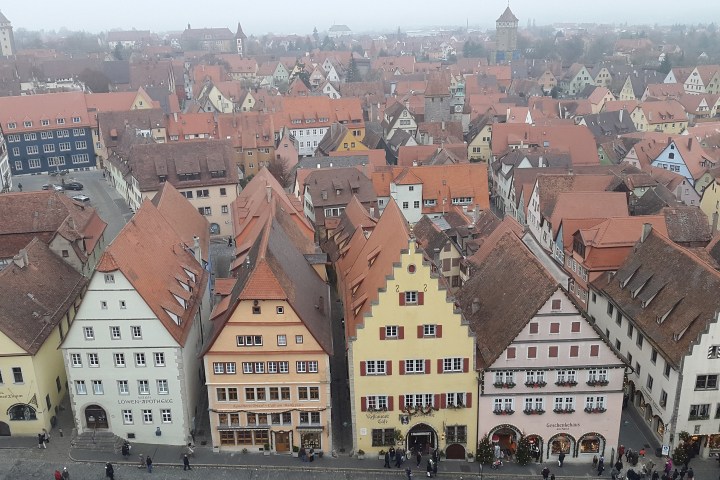 Aerial view of a town with many medieval-style buildings and red-tiled roofs.