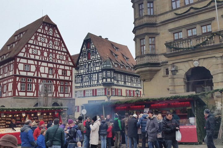 Crowded outdoor market with half-timbered buildings in the background.