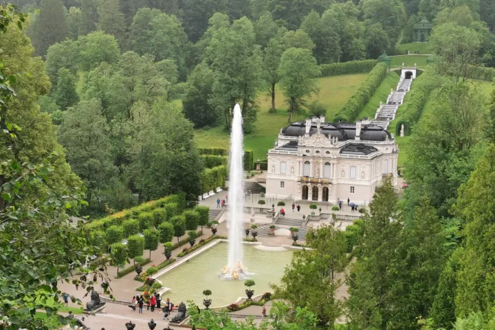Aerial view of a mansion with a fountain and lush gardens.