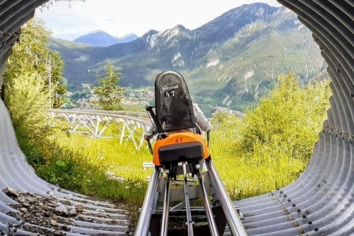 Outdoor roller coaster track exiting tunnel with mountain view