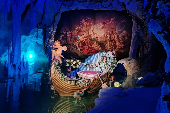 Decorative boat in cave with cherub statue and Renaissance art backdrop.