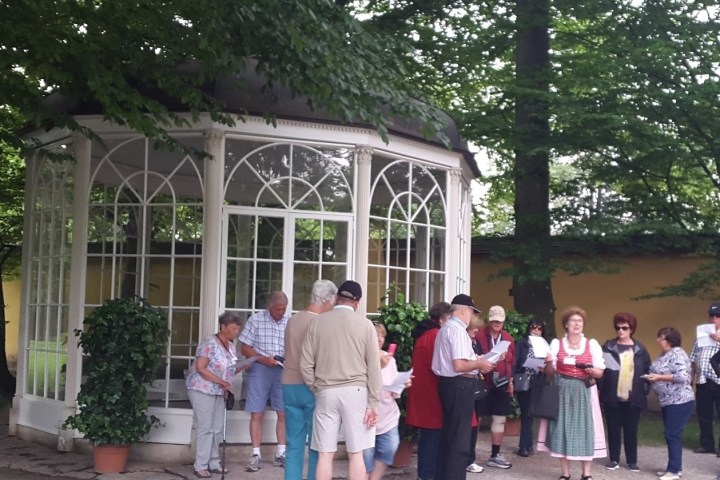 Group of people standing outside a gazebo surrounded by trees.