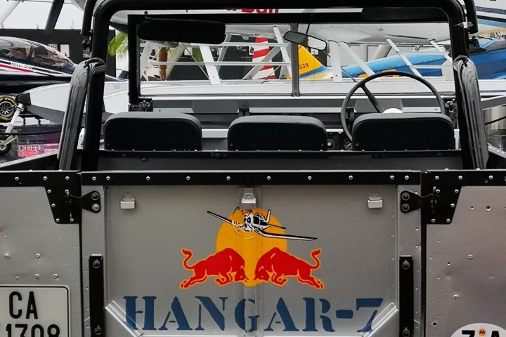 Rear view of an open-top vehicle with 'Hangar-7' logo, parked near small aircraft in a hangar.