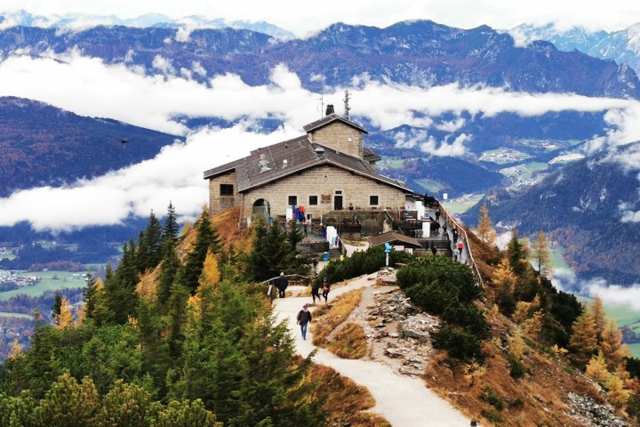 Mountain lodge on a peak surrounded by clouds and scenic landscape in autumn.
