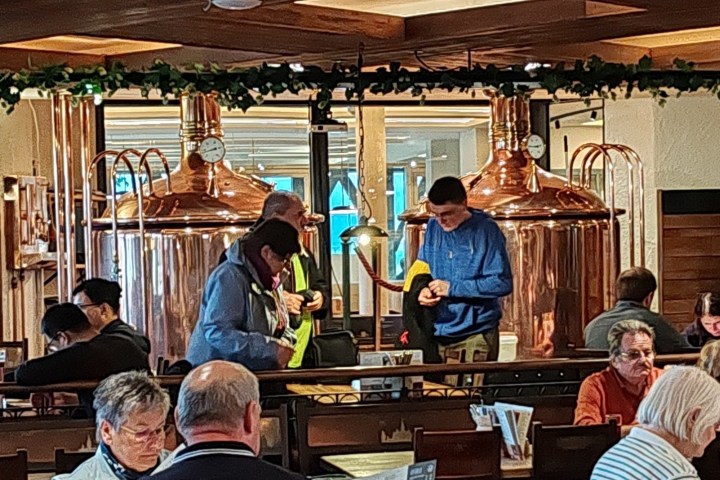 Brewpub interior with copper brewing tanks and people dining at tables.