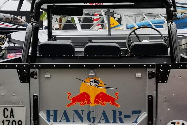 Rear view of a jeep in a hangar with planes, displaying 'Hangar-7' logo.