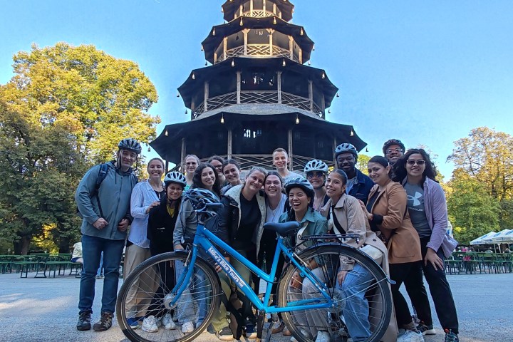 Group of people with bicycles posing in front of a pagoda in a park.