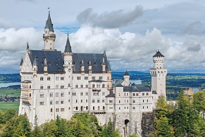 Fairy-tale castle with towers and turrets, set amidst lush green landscape.
