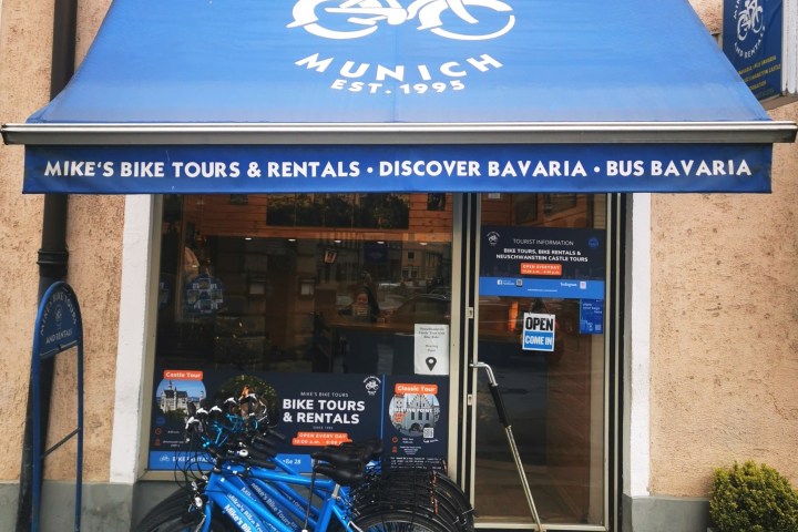 Blue awning over a shop entrance reads 'Mike's Bike Tours Munich,' with bikes parked in front.